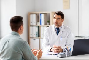doctor with laptop and male patient at hospital